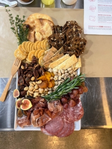 Trays were filled with specialty food items for the boards. A charcuterie board is an appetizer typically served on a wooden board or stone slab, either eaten straight from the board itself or portioned onto flatware. It features a selection of preserved foods, such as cured meats, cheeses and crackers.