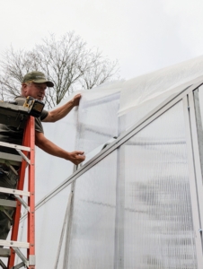 In the back, Doug installs the twin polycarbonate clear wall sheets. Significantly lighter than glass, these sheets are east to install and will insulate the structure from both the front and back.