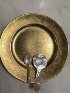 A gold plate with Mother-of-Pearl spoons for the caviar. Pearl is always recommended for caviar because it does not hold flavor, nor does it transfer it, so your caviar will hold exactly as much flavor as intended.