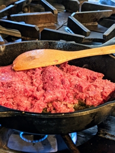 In a large ovenproof skillet over medium-high heat, Elvira starts cooking the beef, breaking up large pieces with the spoon.