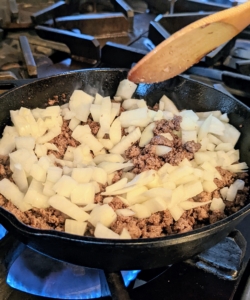 At this step, Elvira has removed any excess fat with a spoon and added the onions. Stirring occasionally, the mixture is cooked until the onions have softened and browned.