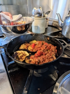 The meat sauce is now in a separate bowl. Elvira layers the eggplant on the skillet and tops it with half of the meat sauce.