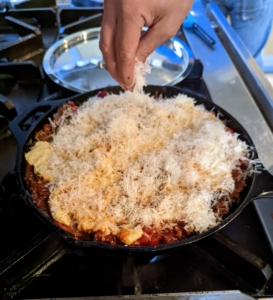 The béchamel is poured over the top and then sprinkled with the remaining Parmesan cheese.