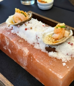 These are dressed oysters - East Coast oysters with baby shrimp, ginger, and pickled vegetables, served on a brick of pink Himalayan salt.