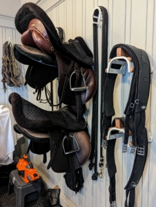 This is my stable tack room where we keep many saddles, bridles, and harnesses. All the equipment is stored on specific racks when not being used.
