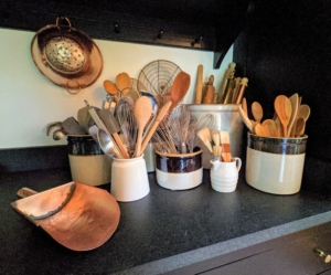 The kitchen has long soapstone counters along two walls of the kitchen and a large soapstone island. These crocks house wooden spoons and other cooking utensils for easy access and sit in one corner.