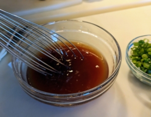 Next, the sauce is prepared. Elvira whisks together the fish sauce, sweet & sour sauce, and two tablespoons sugar.