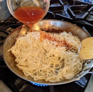 Elvira adds the garlic, noodles and sauce to the skillet stirring and tossing often until the noodles start to absorb the sauce. This takes about two to four minutes.