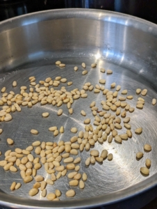 The pine nuts are placed into a skillet without oil and toasted lightly until they are slightly golden and fragrant. Once they're cooked, they're removed from the pan and put aside.
