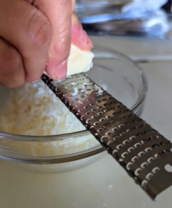 The kit also includes a pre-portioned amount of Parmesan cheese. Elvira grates all the cheese and sets it aside.