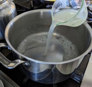 The remaining pasta water is poured back into the pot and heated again over medium-high heat until it is simmering.