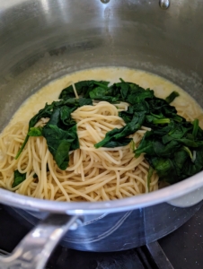 The pasta and spinach are added to the sauce...