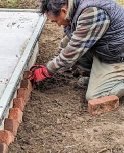 On this side, Pete uses the side of the air conditioner pit as his guide for laying the bricks.