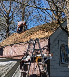 The team works carefully to remove the wooden shingles one by one.