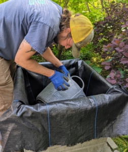 Here is Brian pouring some of the compost to the bottom of the pot, weighing the cloth down in place.