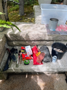 Before we start planting, we make sure all the supplies are ready. Here we have trowels, pruners, hori hori gardening knives, gloves, and plastic bags. The bucket is filled with clay pot shards for drainage in the pots. And a refreshing can of seltzer water, for the gardener at this station of course.