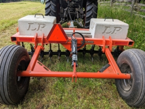 This is our Kubota Land Pride tow-behind spike aerator. We always aerate any field, pasture, or lawn space before seeding. The main reason for any aerating is to alleviate soil compaction. Compacted soils have too many solid particles in a certain volume or space, which prevents proper circulation of air, water, and nutrients. Aerating also improves drainage.