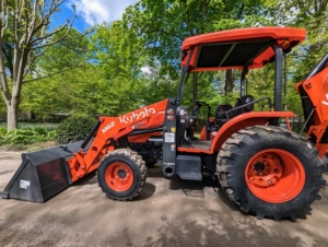 This is our Kubota M62 Tractor Loader Backhoe. This is essential for planting all our large trees. We've been using it quite a bit, especially in the maze. It has a 63 horsepower engine, a front loader with a lift capacity of 3,960 pounds, and a powerful Kubota backhoe with 169.8 inch digging depth.