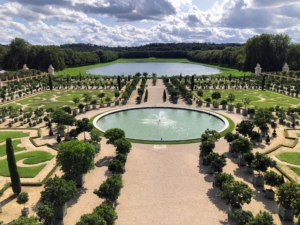 Originally completed in 1663, the Orangerie was intended to supply the much smaller hunting lodge of Versailles and the small retinue, or group of assistants and advisors, which Louis XIV would bring with him in the summer. In 1678, an enlargement of the Orangerie was created by Jules Hardouin-Mansart, which doubled the size of the original. in the distance is the Lake of the Swiss Guards.