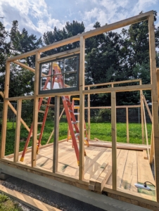 Within a couple of days, the duo gets the framing up for two walls. They also put in one of several windows. The windows are from an old house I took down in Maine next to Skylands. They are perfect for this project.