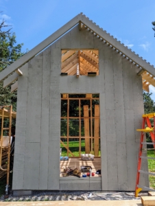 On this warm, sunny day, the framing is all complete and the walls are all going up, plank by plank. Window openings are also framed out on every side.