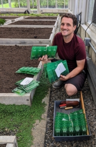 This delivery contains plants for herbs, brassicas, and a variety of lettuces. Ryan takes a selection of plant plugs into the vegetable greenhouse and plans which ones will be planted.
