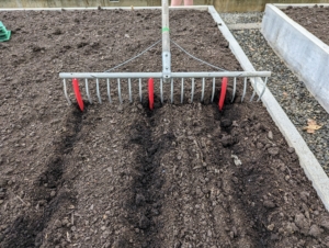 Ryan uses this bed preparation rake from Johnny’s Selected Seeds to create furrows in the soil. Hard plastic red tubes slide onto selected teeth of the rake to mark the rows.