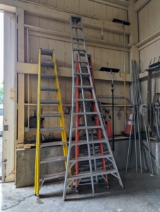 Ladders of various sizes rest against one wall close to one set of large barn doors.