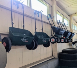 These broadcast spreaders are cleaned and then suspended on hooks, so they are out of the way.