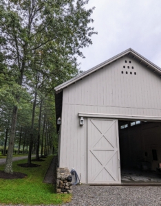 I wanted this Equipment Barn to be an attractive structure in an easy-to-access location. This building is just off the carriage road next to my Pin Oak Allée, hay barn, and vegetable greenhouse. This is one of two giant sliding doors – one at each end.