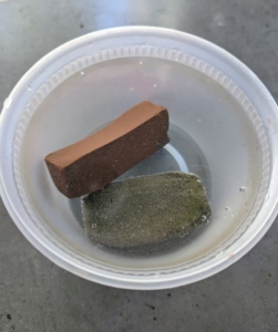 For this task, Brian uses a coarse cleaning block and a whetstone. Both are soaked in water for about 10-minutes before using. A whetstone will help keep the pores of the stone clean, dissipate frictional heat, and ensures smooth sharpening.