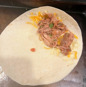 The main ingredient is the tender pulled pork. The pork is sandwiched between the flour tortillas and the cheddar-jack cheese.