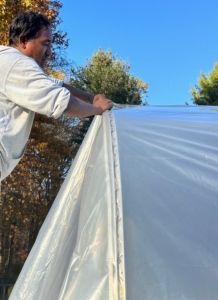 Pete secures the wire at the top of the hoop house and along all the edges.