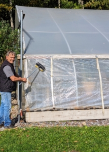 Nearby, Fernando cleans the hoop house. This structure holds my tropical plant collection during the winter. I have four hoop houses here at the farm. They are constructed from steel frames and these polyethylene panels.