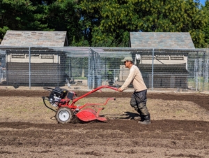 And then Chhiring comes in with our Troy-Bilt Pony Rear-Tine Tiller. The purpose of tilling is to mix organic matter into the soil, help control weeds, break up crusted soil, and loosen the earth for the next planting. One doesn't need to till or break up the soil very deep – less than a foot is fine.