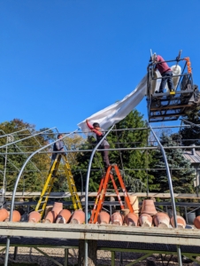 Using our trusted Hi-Lo, Doug, Cesar, Pasang, and Phurba hoist the rolls spooled on steel pipes on top of the frame and start to unroll them. Both fabric pieces must be perfectly in line to cover the structure properly and fully.