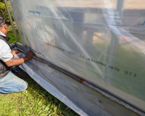 Outside, Pete moves onto the curtains. These manual roll-up curtains attached to a steel pipe that runs along the length of the hoop house will raise and lower the bottom section of the Polyethylene fabric for ventilation when needed.