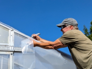 Doug trims any excess plastic around the structure. On the front and back of the hoop house are polycarbonate clear wall sheets. Significantly lighter than glass, these sheets are easy to install and will help insulate the structure from both the front and back.