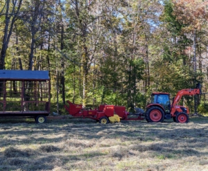 Chhiring has all the proper equipment standing by ready to use. A baler is a piece of farm machinery that compresses the cut and raked crop into compact bales that are easy to handle, transport, and store. The baler is attached to the tractor, and then the hay wagon is attached to the baler.