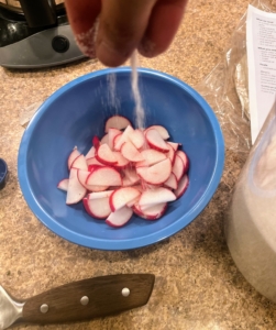 Then Brian mixes the radishes with one tablespoon of vinegar and a pinch each of salt and sugar - this is part of the pickling process.