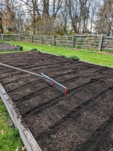 Next, Ryan makes the rows using the bed preparation rake from Johnny's Selected Seeds. This tool allows him to easily create furrows in the soil. Hard plastic red tubes slide onto selected teeth of the rake to mark the rows.