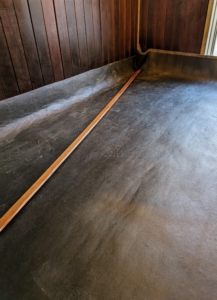 The top layer is a waterproof cover. This is a single piece of latex sheeting that is placed over the entire floor system. Once in the stall, it is pulled tight over the floor so it is flat and level.