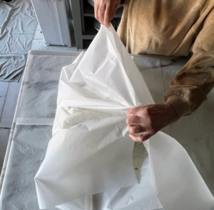 One can purchase big roles of parchment paper, but if it is not big enough, staple two long sheets together and then wrap the turkey.
