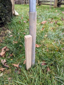 Smaller stakes are pounded into the ground next to each steel ground stake. These short wooden stakes provide points at which the burlap can be secured.