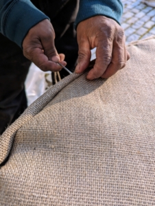 Because the burlap is exposed to the elements for several months, Pete does this task very carefully. The ends at the top are folded over in the same way a gift is wrapped and then sewn closed.