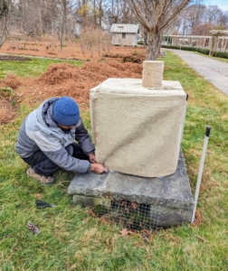 Pete also runs twine underneath the piece to prevent the wind from blowing the burlap off the urn. And underneath all the vessels are shims or small bricks, which keep the urns raised and away from any water or melting snow on the stone surface or ground. All these burlap covers must last through the season without anyone having to redo them.