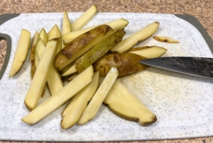 The first step is to prepare the potatoes. All four potatoes are scrubbed clean and then cut into quarter-inch fries.
