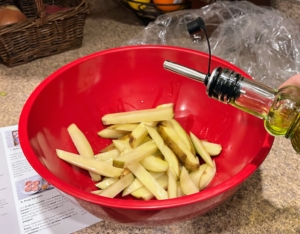 Then, the fries are drizzled with oil and seasoned with salt and pepper.