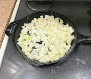 The chopped onions are heated in two tablespoons of oil over medium-high heat with salt and pepper, and then cooked until browned and soft.