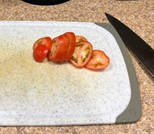 Next, the tomatoes are sliced, and the lettuce is torn to bun sized pieces.